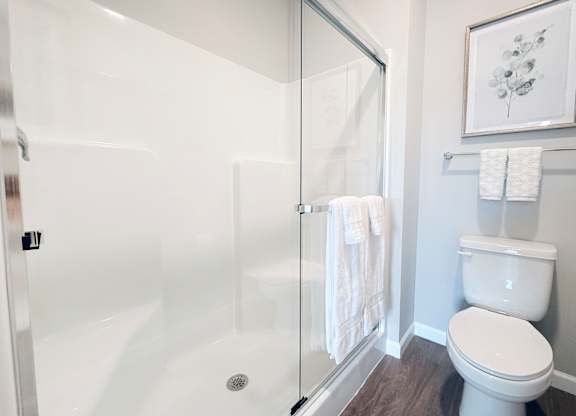 A white toilet sits next to a glass shower stall in a bathroom.