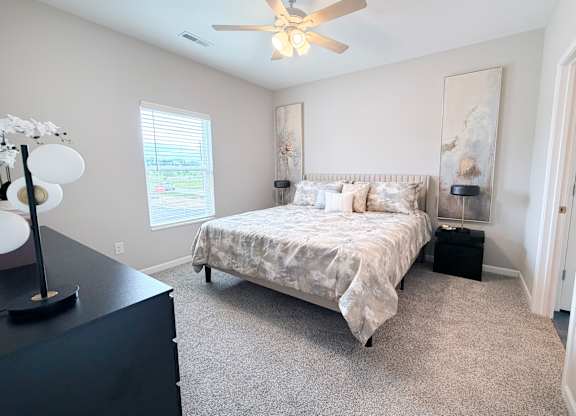 A bedroom with a bed, nightstand, and a ceiling fan.