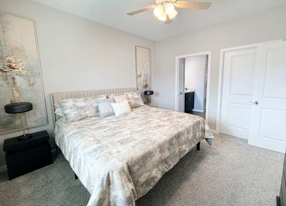 A bedroom with a bed, dresser, and ceiling fan.