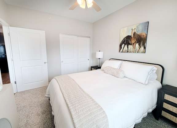 A bedroom with a large bed and a painting of a horse on the wall.