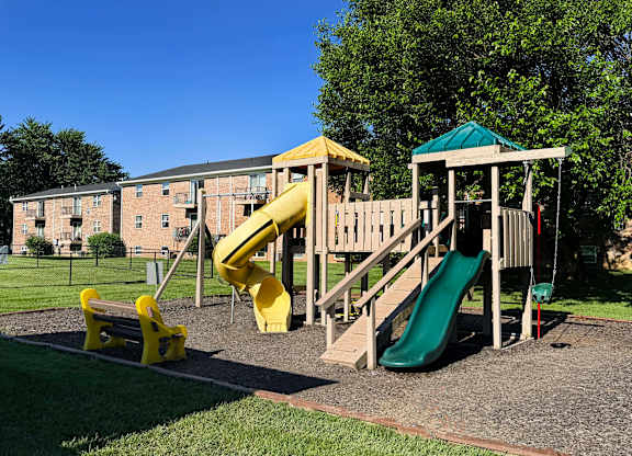 A playground with a yellow slide and a green slide.