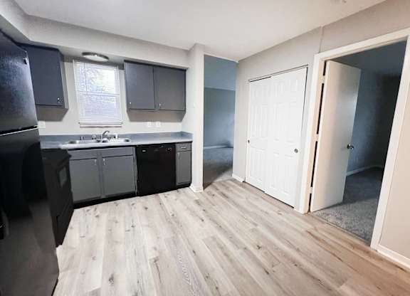 A kitchen with a refrigerator, cabinets, and a sink.