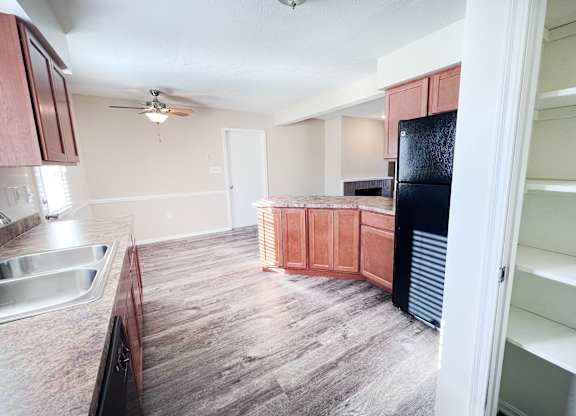 A kitchen with wooden cabinets and a black fridge.