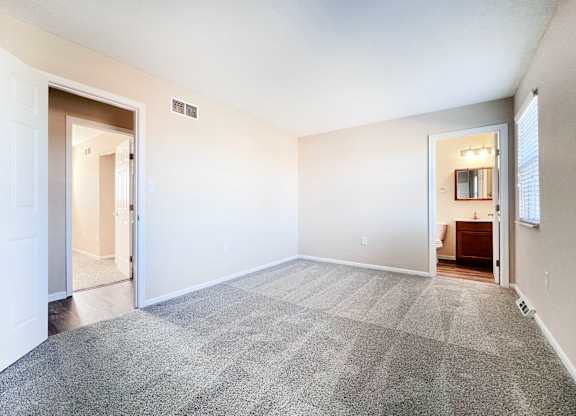 A spacious room with a carpeted floor and white walls.