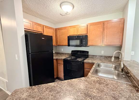A kitchen with black appliances and wooden cabinets.