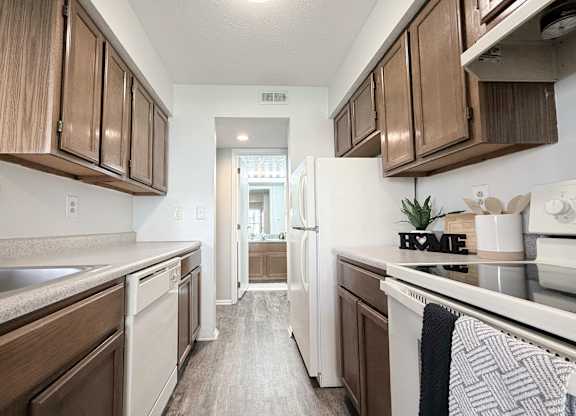 A kitchen with brown cabinets and a white fridge.