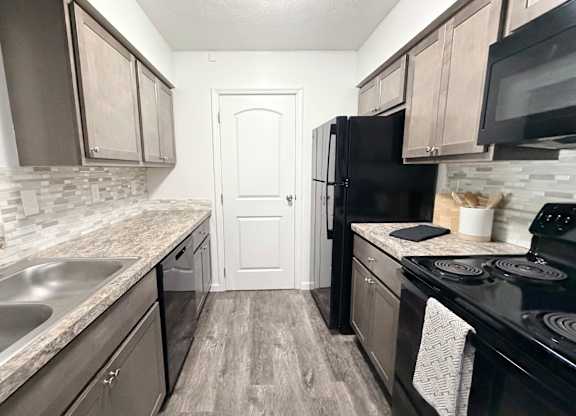 A kitchen with black appliances and wooden cabinets.
