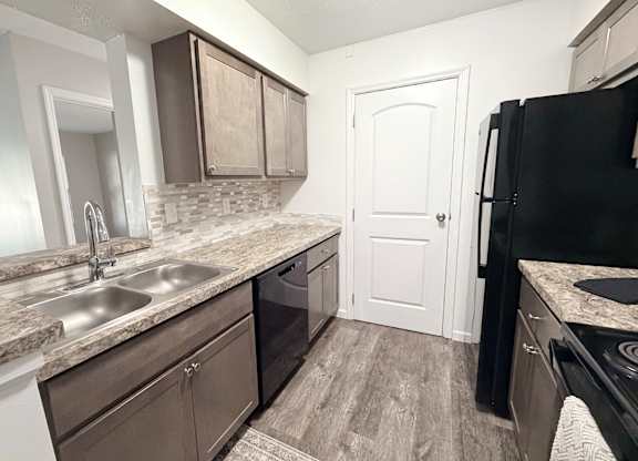 A kitchen with a black refrigerator and brown cabinets.