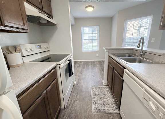 A kitchen with white appliances and brown cabinets.