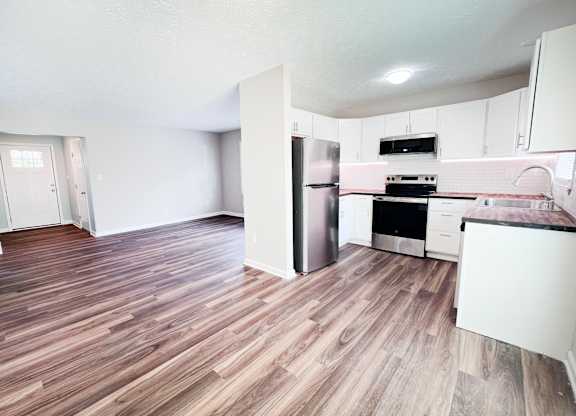 A kitchen with a refrigerator, oven, and stove top.