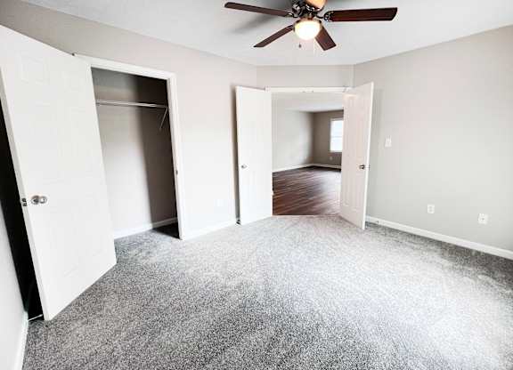 A room with a ceiling fan and carpeted floor.