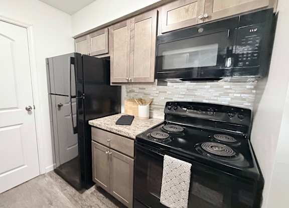 A black stove and refrigerator in a kitchen.