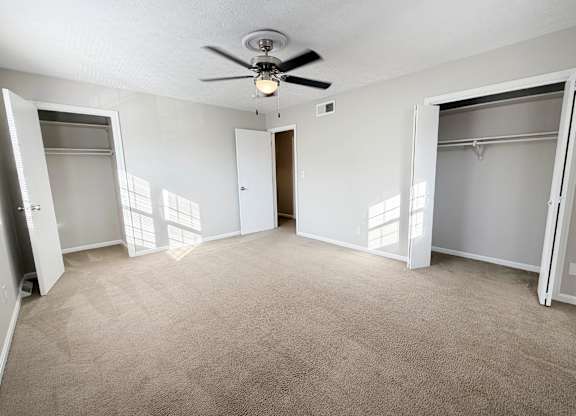 A room with a ceiling fan and carpeted floor.