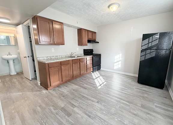 A kitchen with wooden cabinets and a black refrigerator.