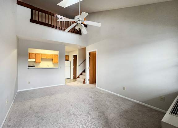 A room with a ceiling fan and a staircase.