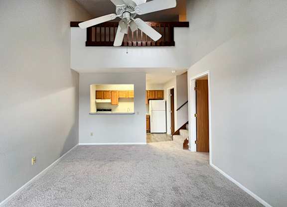 A room with a ceiling fan and a window with blinds.