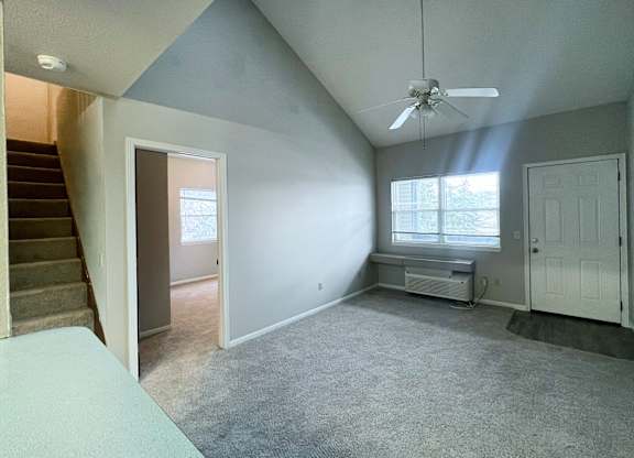 A room with a staircase on the left and a window with a bench on the right.