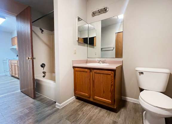 A bathroom with a toilet, sink, and mirror.
