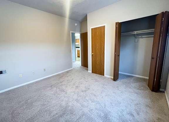 A spacious room with a carpeted floor and a door on the right side.
