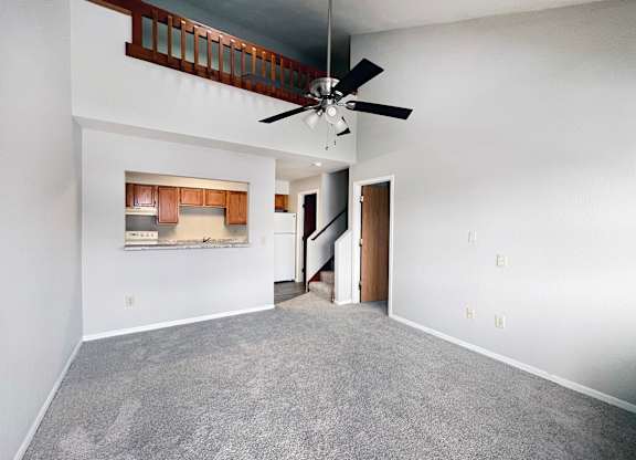 A room with a ceiling fan and a staircase.