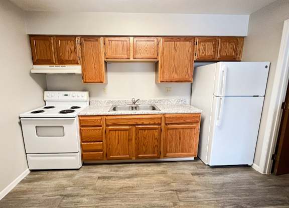 A kitchen with wooden cabinets and a white refrigerator.