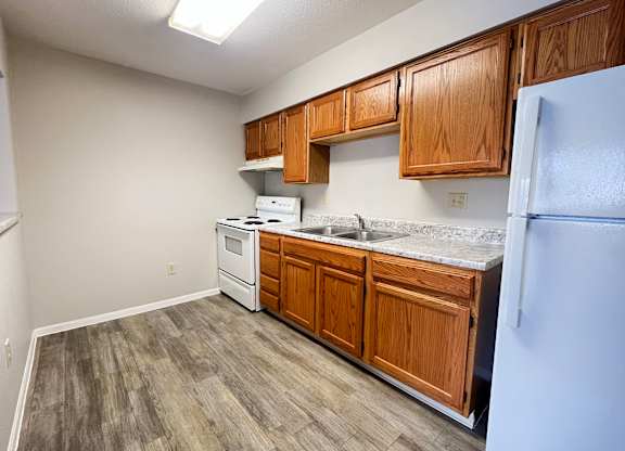 A kitchen with wooden cabinets and a white fridge.