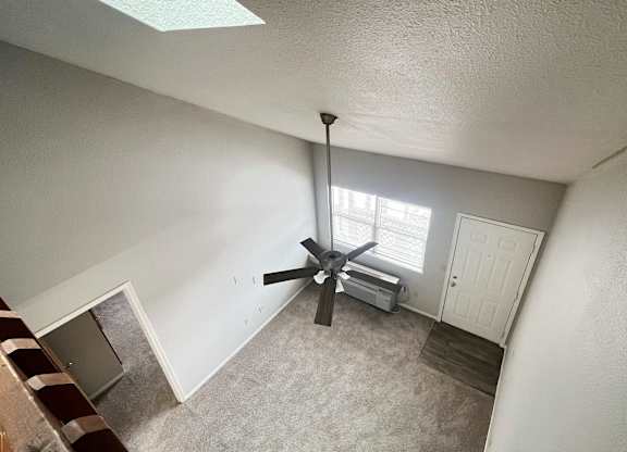 A room with a ceiling fan and a window.