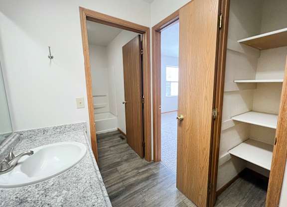 A bathroom with a sink, mirror, and wooden cabinet.