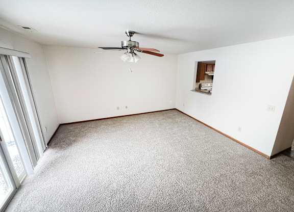 A room with a ceiling fan and carpeted floor.