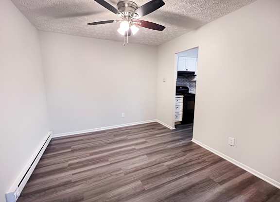 A room with a ceiling fan and wooden flooring.