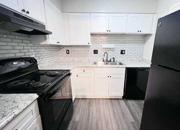 A kitchen with black appliances and white cabinets.