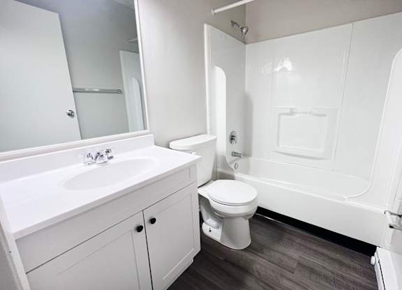 A white bathroom with a toilet, sink, and bathtub.