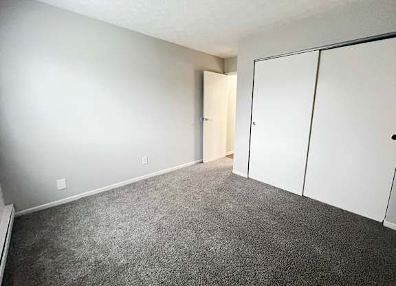 A room with a carpeted floor and a white door.