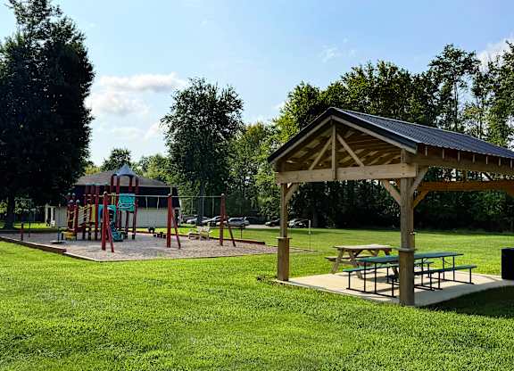 A playground with a swing set and picnic tables.