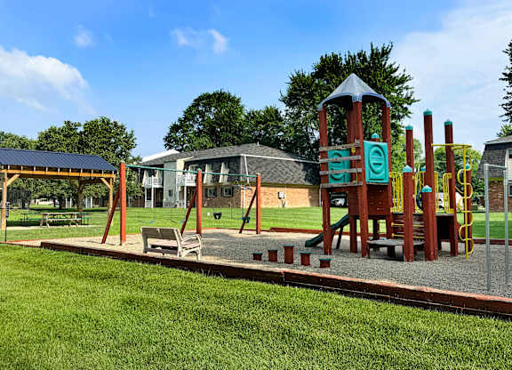 A playground with a wooden swing set and a green slide.