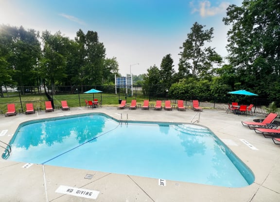 a swimming pool with red lounge chairs and umbrellas  at Hunter's Creek Apartments, Cincinnati, 45242