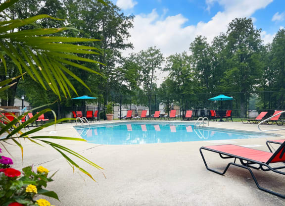 a swimming pool with red chaise lounge chairs and umbrellas  at Hunter's Creek Apartments, Cincinnati, Ohio