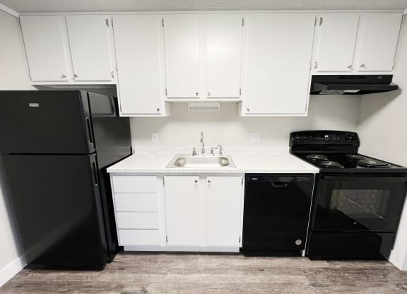 a kitchen with white cabinets and black appliances and a black refrigerator  at Wentworth Estates Apartments, Florence, Kentucky