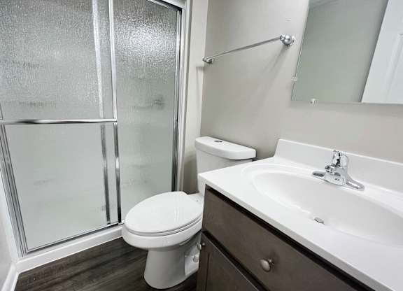 A white toilet sits next to a sink in a bathroom at Revere Village Apartments, Ohio, 45458