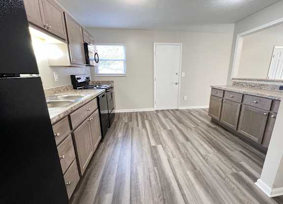 A kitchen with a black refrigerator and wooden floors at Revere Village Apartments, Centerville, Ohio