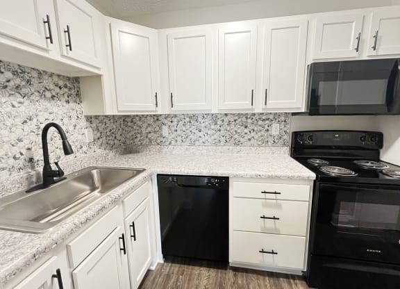 a kitchen with white cabinets and black appliances and a sink at 450 on Keeneland Apartments, Richmond, KY