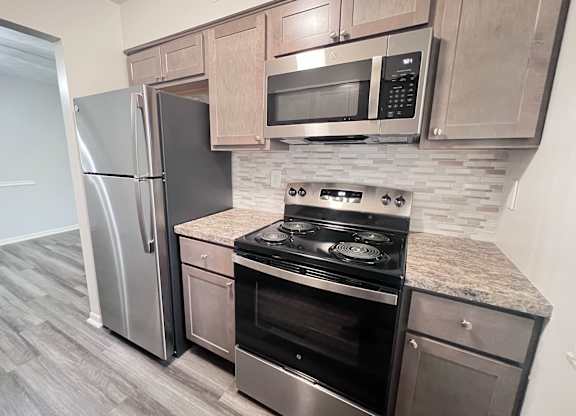 A kitchen with a stove, refrigerator, and microwave.