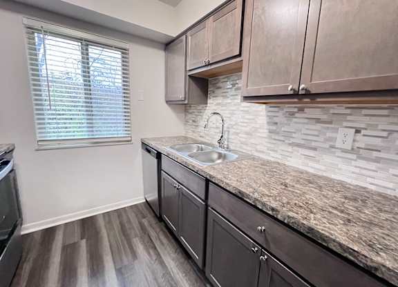 A kitchen with a granite countertop and wooden cabinets.