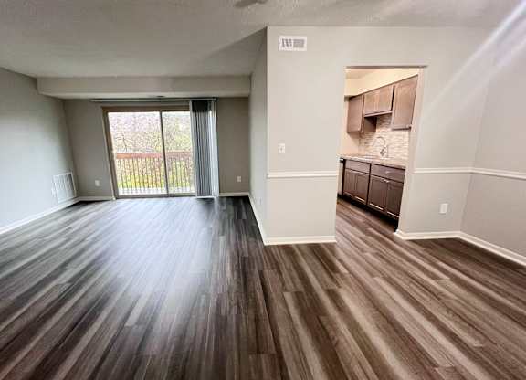 A room with wooden flooring and a sliding glass door.