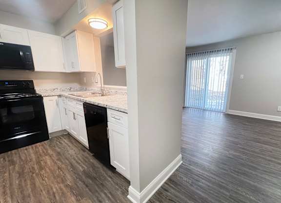 A kitchen with black appliances and white cabinets.