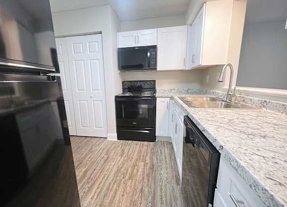 A kitchen with a black oven and white cabinets.