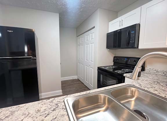 A kitchen with a black fridge, black oven, and black microwave.