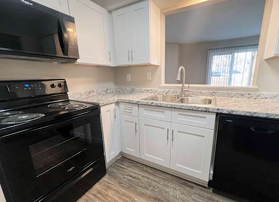 A kitchen with black appliances and white cabinets.