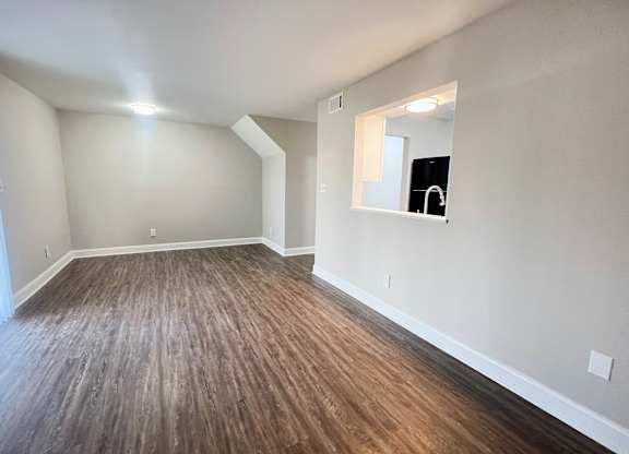 A room with wooden flooring and a mirror on the wall.