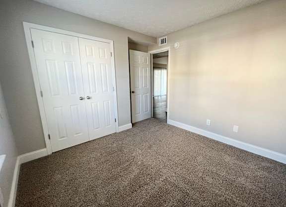 A room with a carpeted floor and two doors.